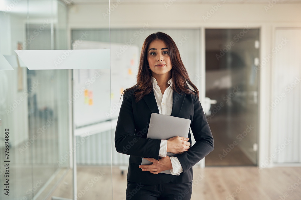 Confident businesswoman standing with a laptop at the entrance to a boardroom Confident businesswoman standing with a laptop at the entrance to a boardroom