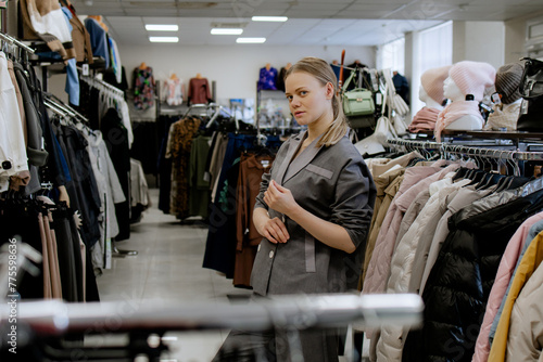 Woman is shopping for casual clothes, grey costume fashionable women's clothing store, in boutique inspecting differents blouses price tags and the quality of fabric. Shopping in Clothing Store. 