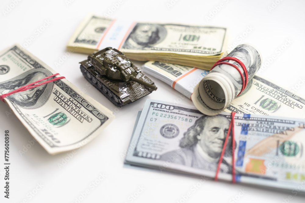 Fototapeta premium Toy tank on US hundred dollar bills banknotes close up. The concept of war costs, military spending and economic crisis
