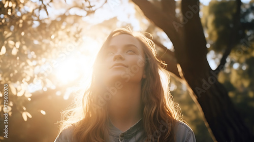 Portrait of Young Woman Enjoying the Warmth of the Sunset Light Filtering Through the Forest