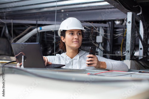 female electrician installing electric device in ceiling