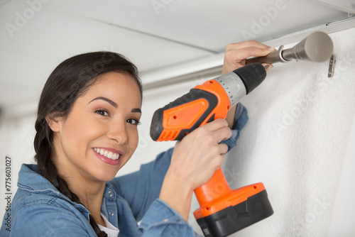 woman putting up curtain rail with a battery screwdriver
