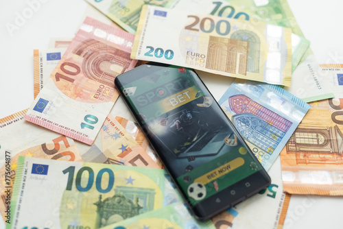 Smartphone with gambling mobile application with money close-up. Sport and betting concept