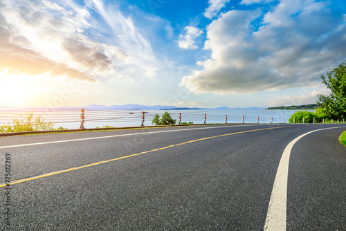 Asphalt road and lake with sky clouds at sunset © ABCDstock