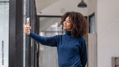 Smiling curly-haired woman enjoying taking a selfie with her smartphone in a bright and airy office space.. Free Download Smiling curly-haired woman enjoying taking a selfie with her smartphone in a bright and airy office space.. - GFXLoad