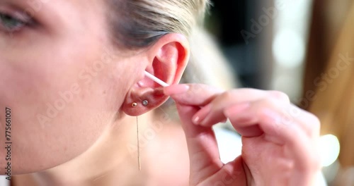 Girl uses cotton swab for ear for cleaning. Daily hygiene concept woman and liner close to ear photo