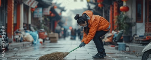 Local resident tidying up wet alley in old Chinese neighborhood. Street cleaning and urban lifestyle concept