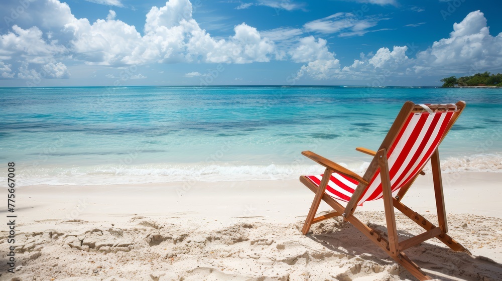 Red and white striped beach chair on pristine tropical beach with clear blue water and fluffy clouds.