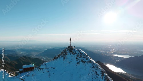 Aerial View Of Cross of Punta Cermenati On Snow Covered Peak At Monte Resegone. Circle Dolly With Sun Shining In background photo