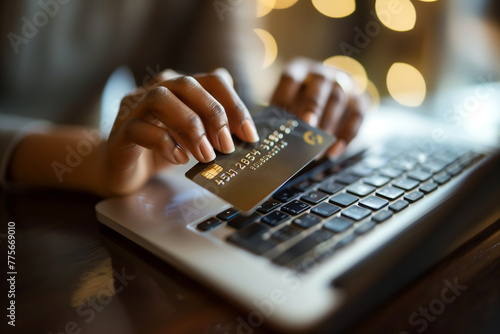 A close-up of a person's hands holding a credit card and making a payment online. Hand holding credit card over laptop keyboard for online payment