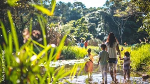 Children and adults walking through shallow water in lush park.
