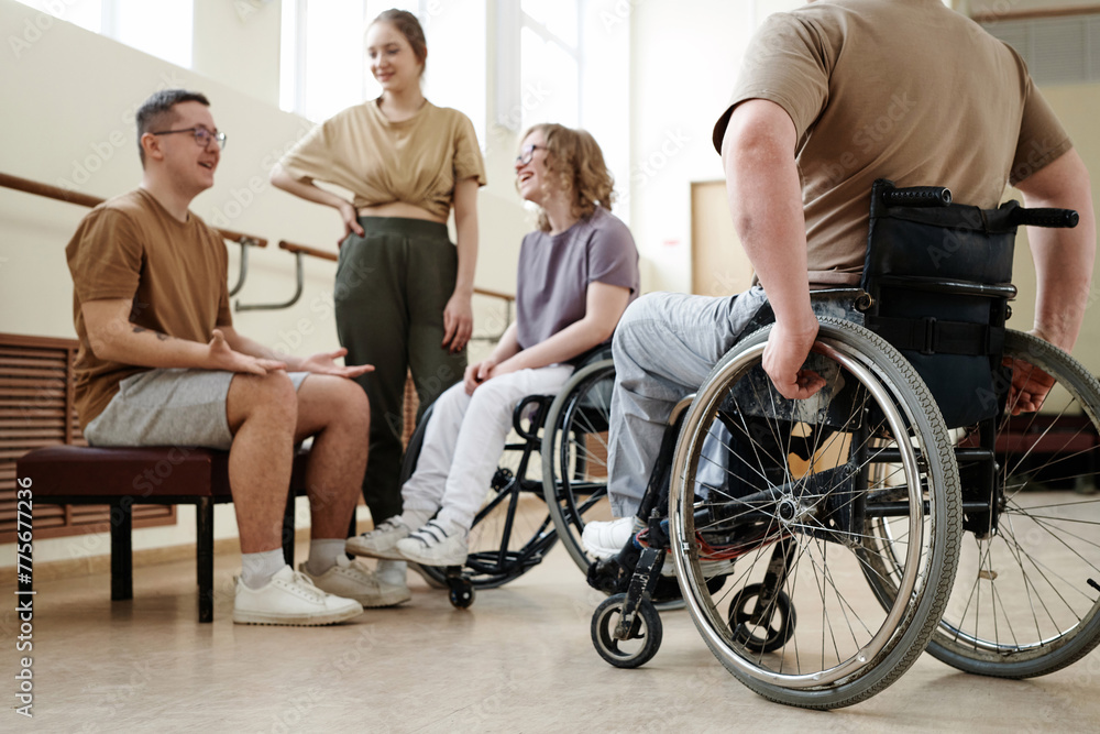 Low angle view selective focus shot of wheelchair dancers and their partners relaxing and chatting during break Low angle view selective focus shot of wheelchair dancers and their partners relaxing and chatting during break