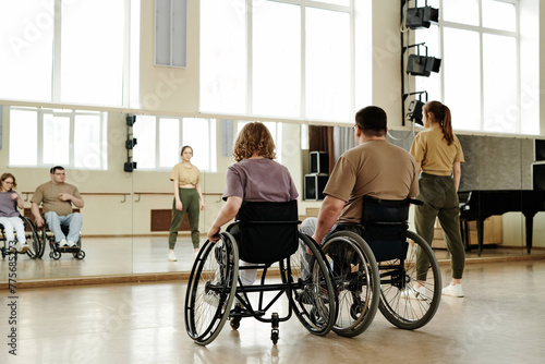 Rear view diverse people practicing dance with wheelchairs in front of mirror in studio, long shot