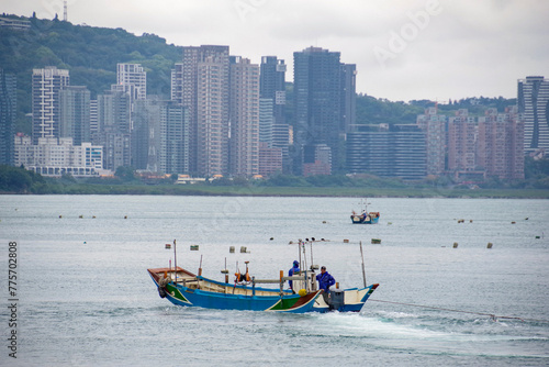 ムール貝を収穫する漁船と淡水の街並み