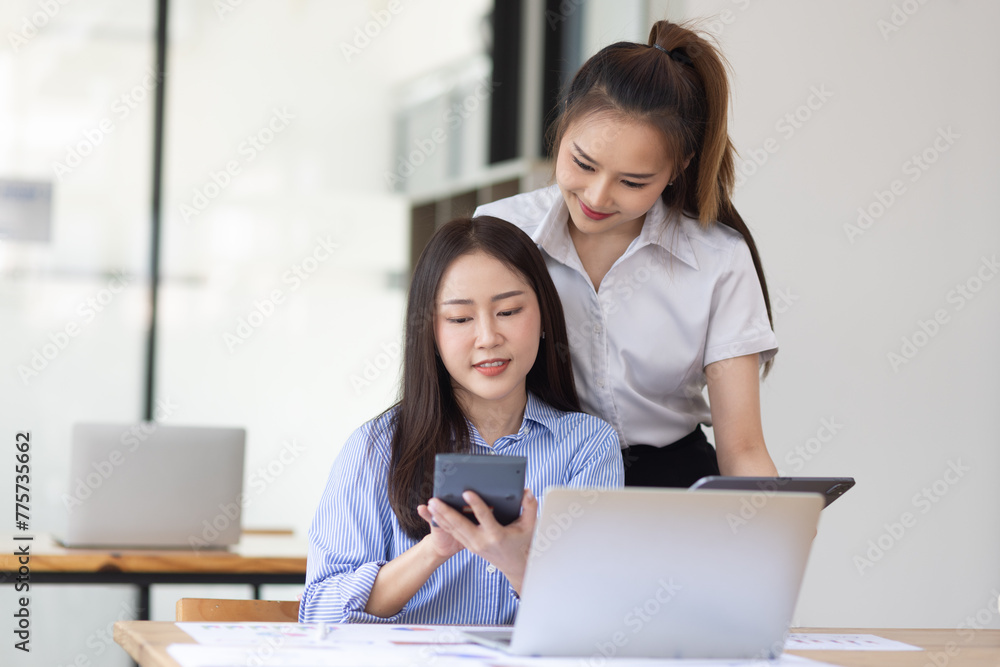 Two young asian business workers using touchpad reading document working at office. Two young asian business workers using touchpad reading document working at office.