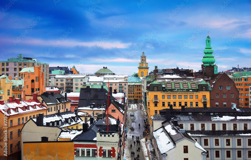 Beautiful cityscape - City museum, Church, traditional houses covered with snow and people go trough the street at the background of cloudy sky in Sodermalm, Stockholm, Sweden, Northern Europe
