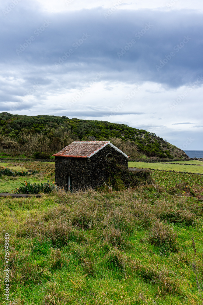 A typical Azorean house, built of black volcanic rock, nestled in a cove on an autumn afternoon. A typical Azorean house, built of black volcanic rock, nestled in a cove on an autumn afternoon.