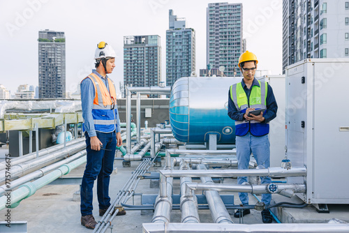 engineer teamwork technician workers service hotel boiler tank hot water supply pipe system. team working safety checking maintenance pipeline heating water delivery line at roof top outdoor. photo