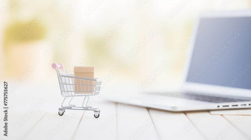 Mini Tiny cart with boxes beside laptop with blur background. Concept banner online shopping E-commerce.