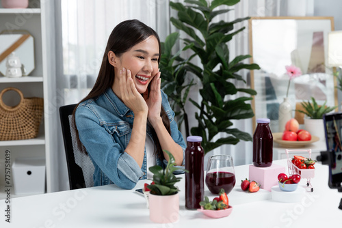 Smiling young beautiful Asian reviewing tasty mixed strawberry and cherry juice detox drinks  showing healthy product to promote for special promotion selling on social media online record. Stratagem.