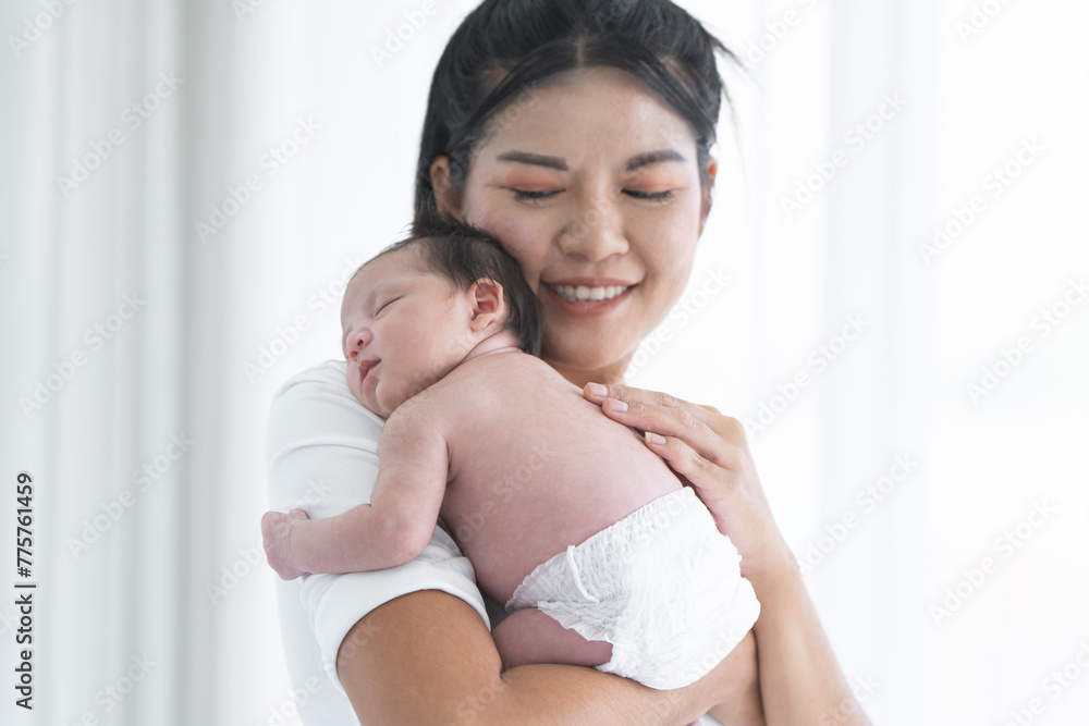 Mother carrying her newborn baby girl on shoulder at home. Cute 19 days Asian Australian infant baby sleeping in mom arms. Parent and little kid relaxing together. Selective focus on child Mother carrying her newborn baby girl on shoulder at home. Cute 19 days Asian Australian infant baby sleeping in mom arms. Parent and little kid relaxing together. Selective focus on child