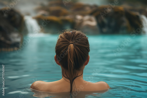 Beautiful young woman relaxing in hot springs pool in Iceland. Female traveler enjoying thermal bath in hot springs in Iceland.