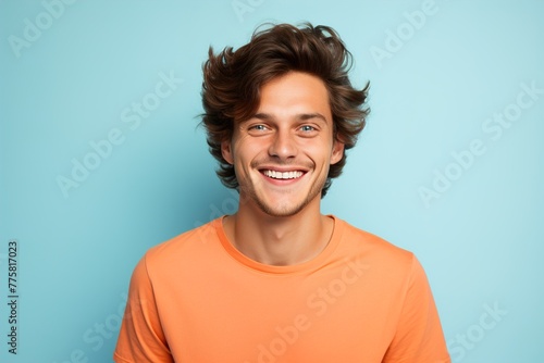 A man with a bright orange shirt is smiling and looking at the camera