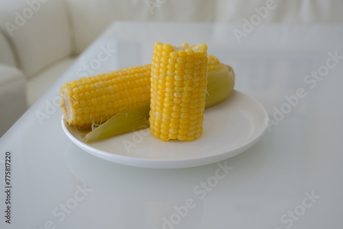 yellow corn on a white plate. boiled yellow corn on white plate and white table