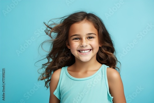 A young girl with long hair is smiling and wearing a blue tank top