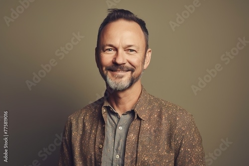 A man with a beard and a smile is wearing a brown shirt photo