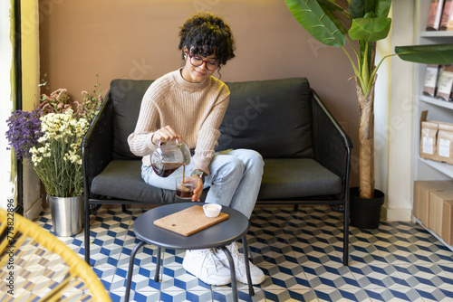 Latin woman pouring cold brew coffee indoors with stylish decor photo