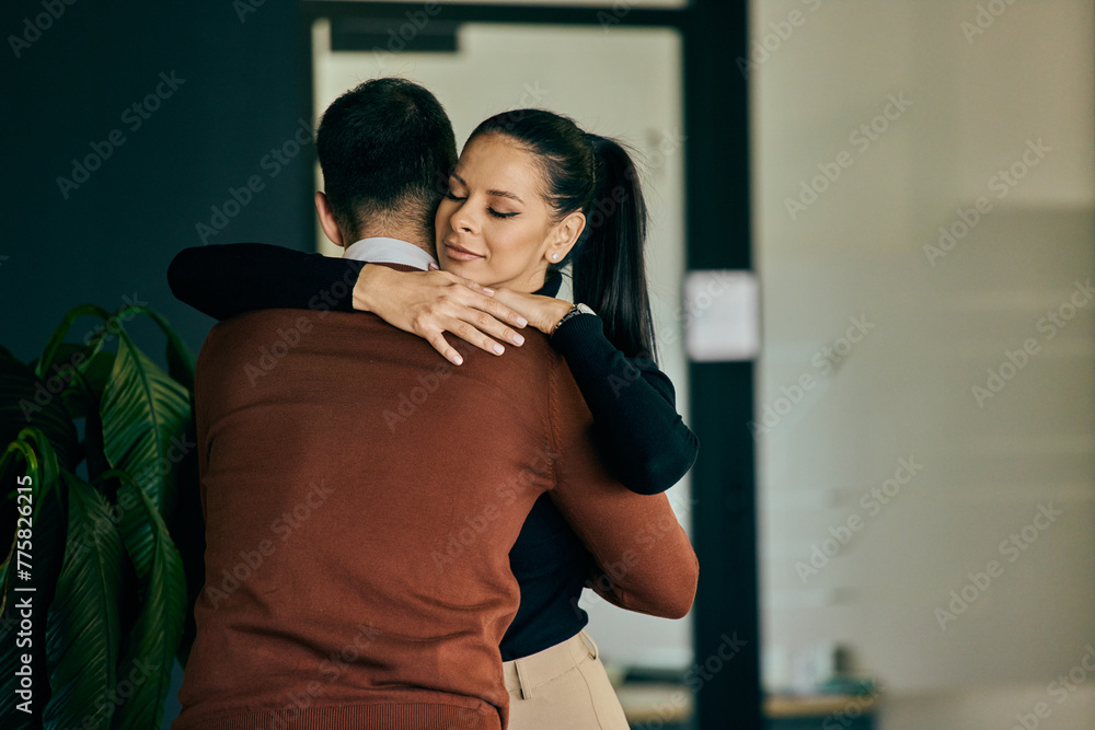 Two colleagues hugging at the office, male and female. Two colleagues hugging at the office, male and female.