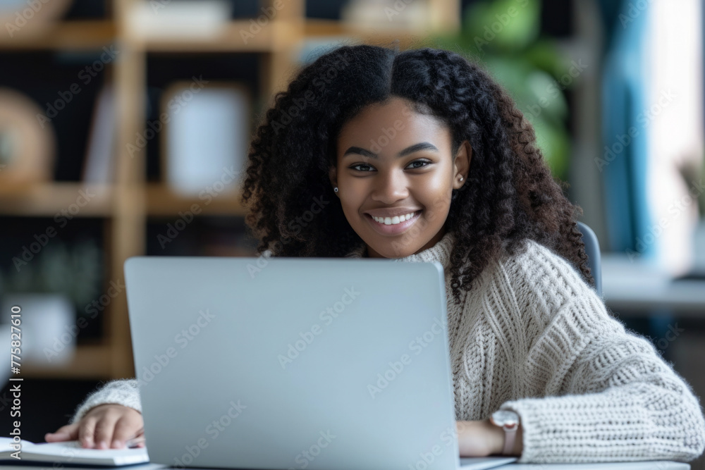 Smiling African American Girl studying with laptop computer. Teenage girl sitting at her desk and writing in notebook. Smiling African American Girl studying with laptop computer. Teenage girl sitting at her desk and writing in notebook.