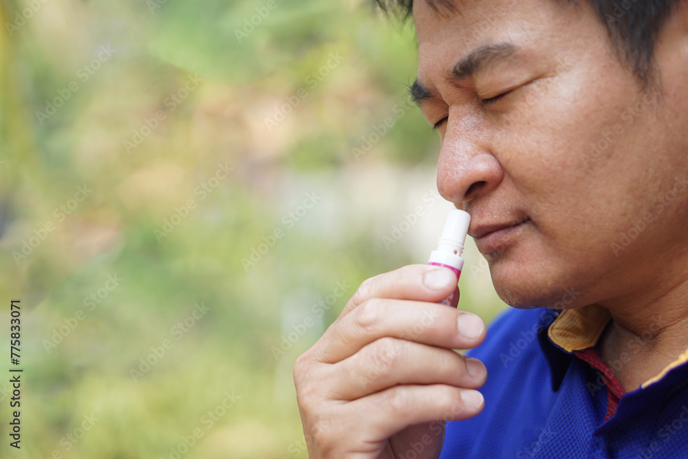 Asian man use menthol inhaler to smell for relief symptom of dizzy from hot weather condition. Concept, self first aid to protect from heat stroke. Refreshing. Aroma therapy.       - obrazy, fototapety, plakaty 