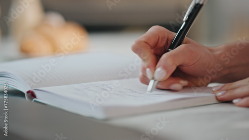 Woman hands writing notebook holding ballpen closeup. Accountant working laptop 