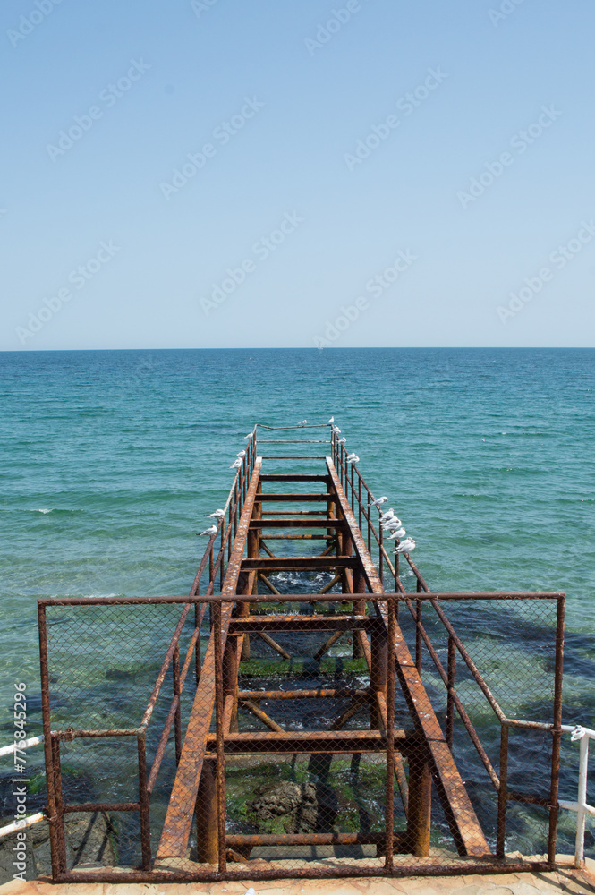 Melancholical rusty iron pier with seagulls diving into the Black Sea in Sozopol, Bulgaria