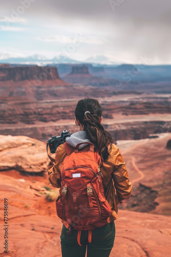 A female traveler gazes upon a vast canyon, holding a camera, ready to capture the breathtaking landscape before her