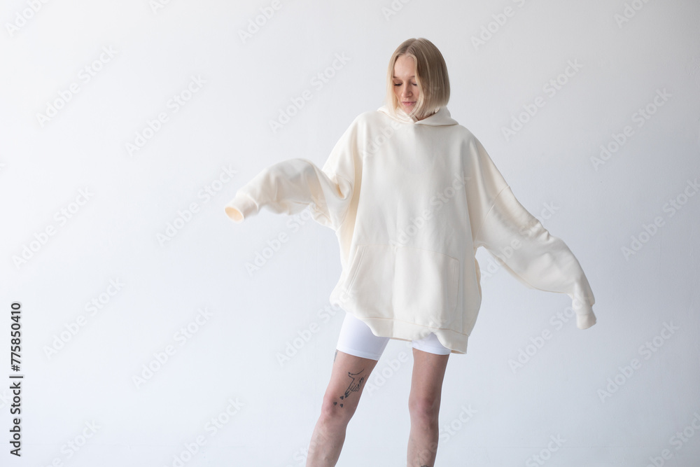 Beautiful blonde woman posing in white hoodie and leggings posing against white background Beautiful blonde woman posing in white hoodie and leggings posing against white background