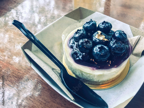 Close up a Blueberry cheesecake on a wooden table with natural light from the window.