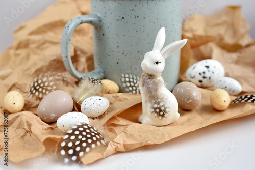 Easter composition with white rabbit, eggs and feathers on a brown kraft paper background. Easter still life