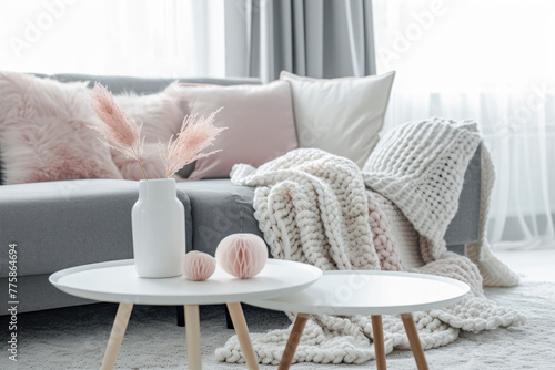 A cozy living room with a modern sofa, decorative pillows, a knitted blanket, and a table with decorative items photo