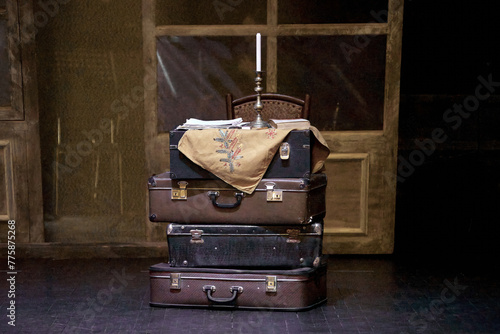 bunch of suitcases on a theater stage with candles in a candlestick .