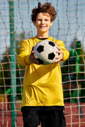 A young man stands in front of a net  holding a soccer ball in his hands  ready to take a shot. He is focused and determined  with the goal in his sights.