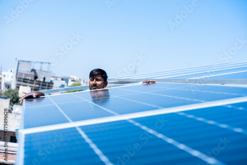 Indian worker installing solar panels on roof of house. Maintenance of photovoltaic panel system. Concept of alternative, renewable energy.Copy space
