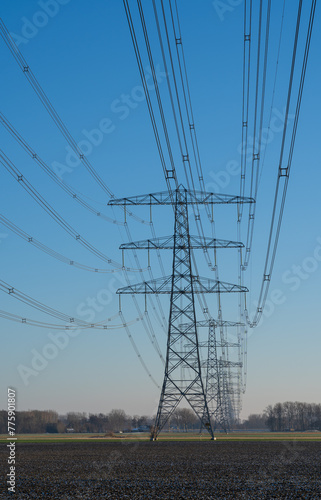 A row of electrical towers on a sunny day in the countryside. © sanderstock
