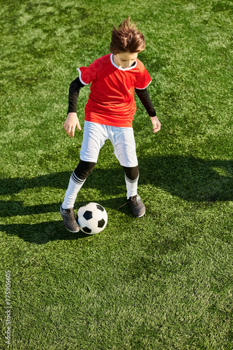 A young boy is energetically kicking a soccer ball on a green field. His concentration is evident as he practices his skills, aiming for precision and power with each kick. © LIGHTFIELD STUDIOS