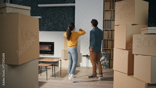 Couple watching new house living room full boxes. Family discussing interior  photo
