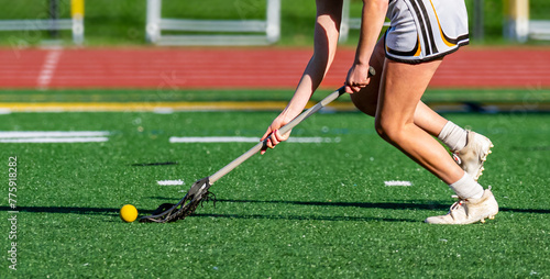 Принти на полотні A young girl on the Varsity Lacrosse team reaches as ahead of her for the ball