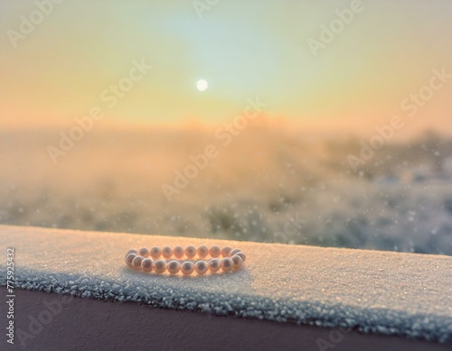 Pearls placed on a frost-covered window ledge, the early morning frost accentuating their cool tones against the warm sunrise