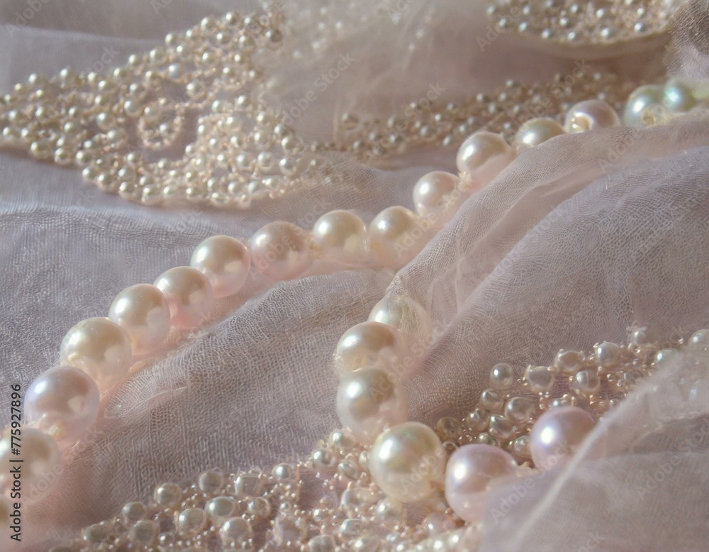 Pearls strewn across delicate lace fabric, the texture of the lace enhancing the smoothness of the pearls, set in a soft, romantic light